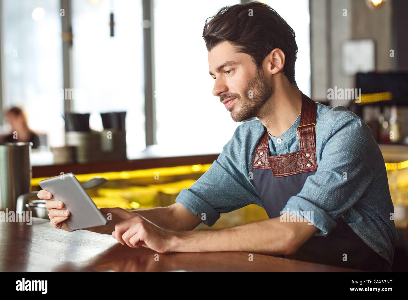 Professional Occupation. Bartender leaning on counter playing game on digital tablet joyful Stock Photo