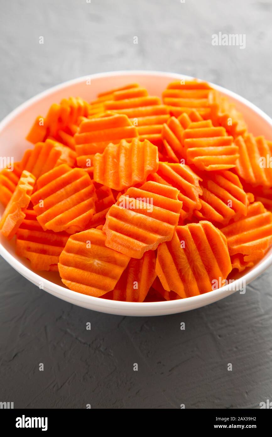 Fresh Raw Organic Carrot Chips in a bowl over gray background, low angle view. Close-up. Stock Photo