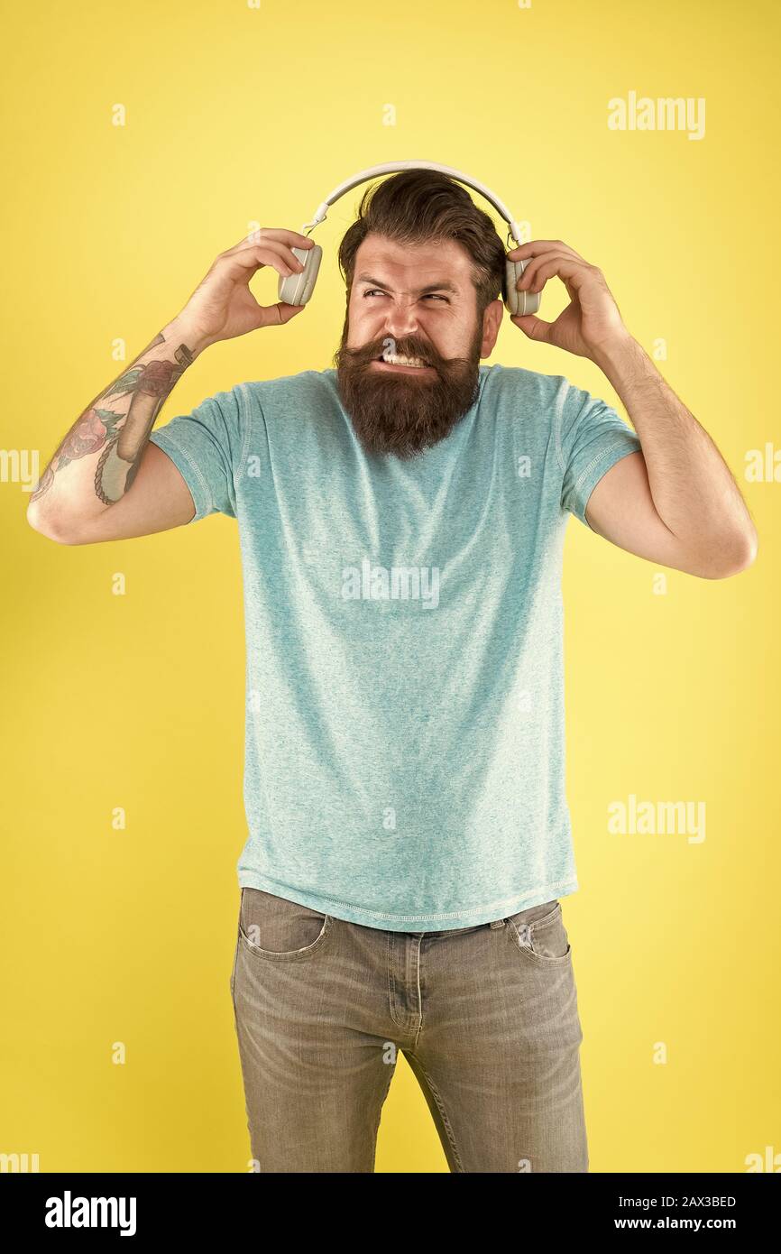 Make some noise. Sound is so loud. Bearded man listen to sound track. Hipster wear earphones playing sharp sound. Unpleasant sound. Music and technology. Stock Photo