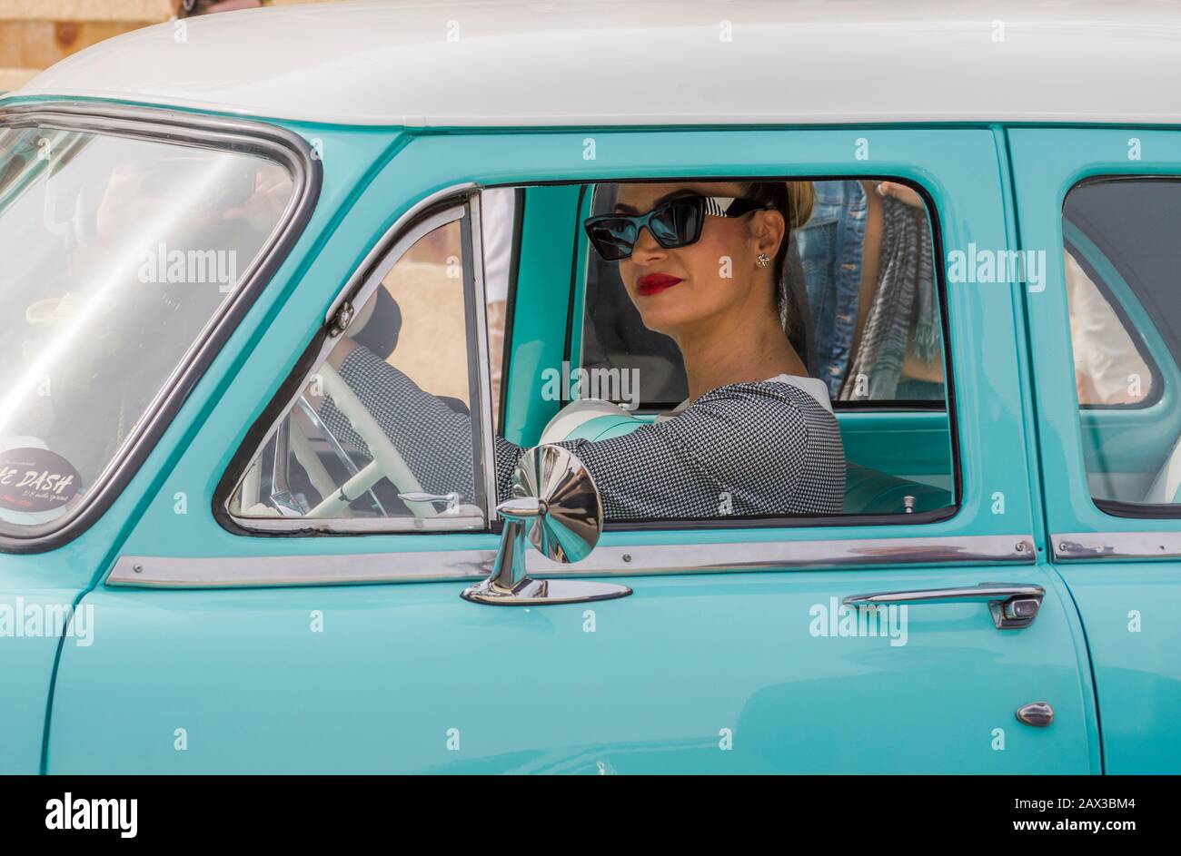 Woman in fifties style in classic car of the fifties driving, Torremolinos, spain. Stock Photo