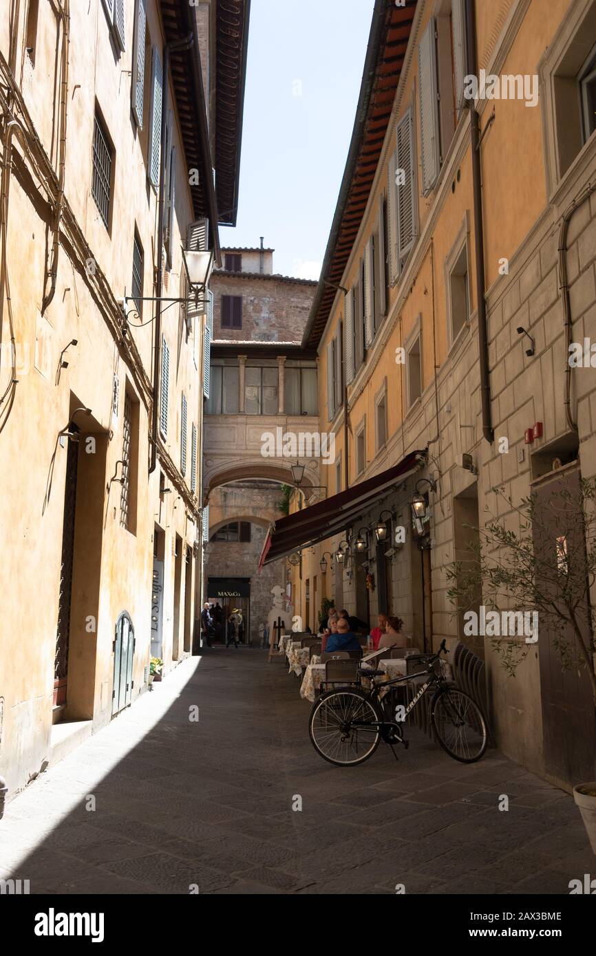 Diners at restaurant in a narrow Seina street Tuscany Italy Stock Photo