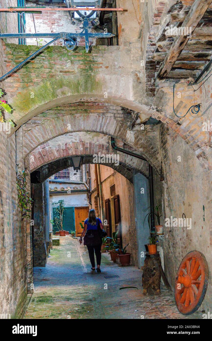 Vicolo delle Carrozze a small road passing under old houses, arches and balconies in Sienna Tuscany Italy Stock Photo
