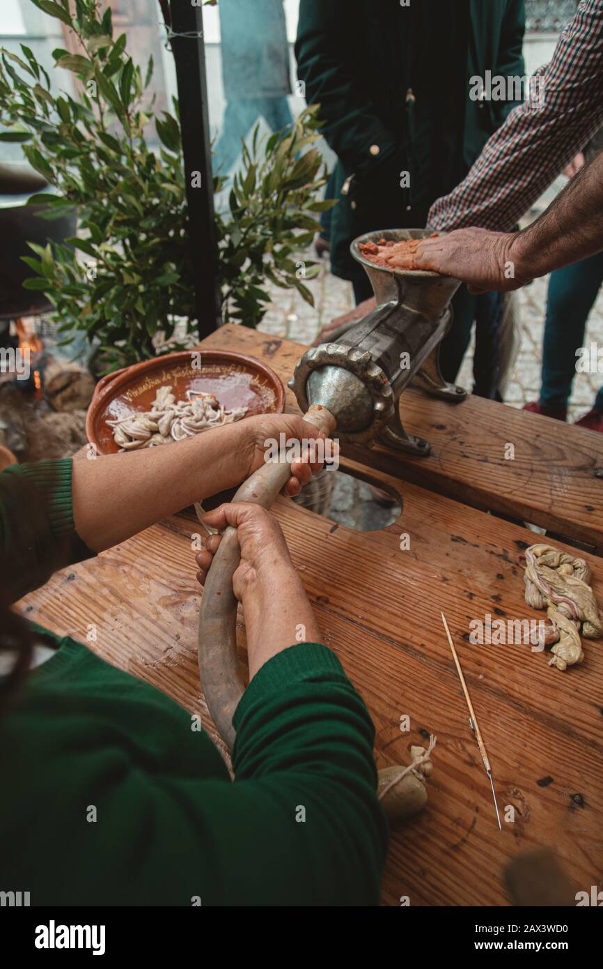 People grinding meat with an old fashioned meat grinder on a wooden