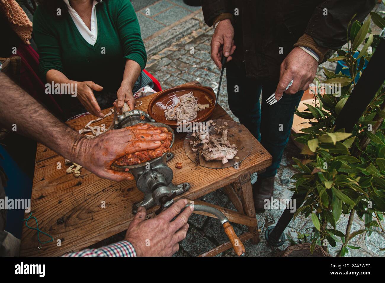 Group of people grinding meat with an old fashioned grinder and