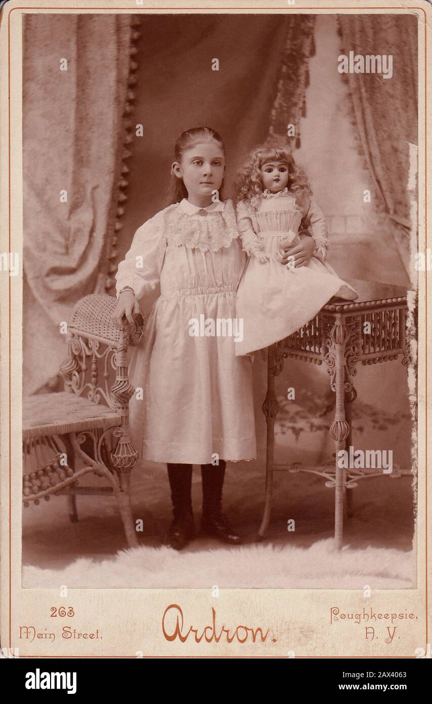 1900 ca, New Yersey , USA : Little girls with doll . Photo by Ardron , Poughkeepsie , New Yersey  - FOTO STORICHE - HISTORY PHOTOS -  BAMBINA -  CHILD - BAMBINO - BAMBINI - BAMBINE - CHILDREN -  tenerezza - tenderly - CHILDREN - BAMBINA - BABY - BELLE EPOQUE - FASHION - MODA INFANTILE - BABY -  bebé  - pink dress - CHILDHOOD - INFANZIA - bambola - bambole - toys - giocattolo - giocattoli - gioco - play - poltrona di vimini - rattan - pizzo - lace   ----- Archivio GBB Stock Photo