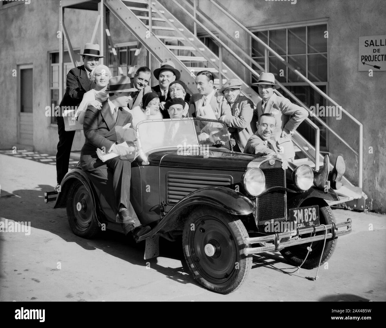 1931 , february , LOS ANGELES , USA  : The american silent movie actor and director BUSTER KEATON ( 1895 - 1966 ) in a pubblicity still with all the cast of the movie BUSTER SE MARIE , french version of his movie ' Parlor , Bedroom and Bath ' ( Io ... e le donne ) by Claude Autant-Lara and  Edward Brophy . The smiling man at the front of the car is comic actor George Davis.   Back ti him the movie director CLAUDE AUTANT-LARA with hat and hand at his side. Around Buster Keaton the actress of the movie: Françoise Rosay , Jeanne Helbling and Lya Lys ( 1908 – 1986 ). - SILENT MOVIE - CINEMA MUTO Stock Photo