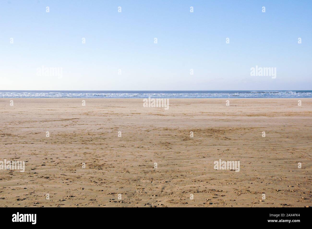 Large empty sandy beach with golden sand leading to the ocean Stock Photo