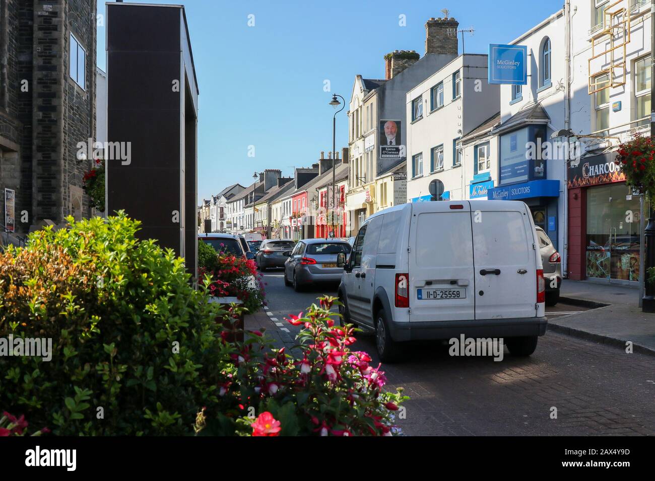 A white van parked in a line of traffic in a narrow one-way street on a sunny autumn morning with blue sky in Letterkenny County Donegal, Ireland., Stock Photo