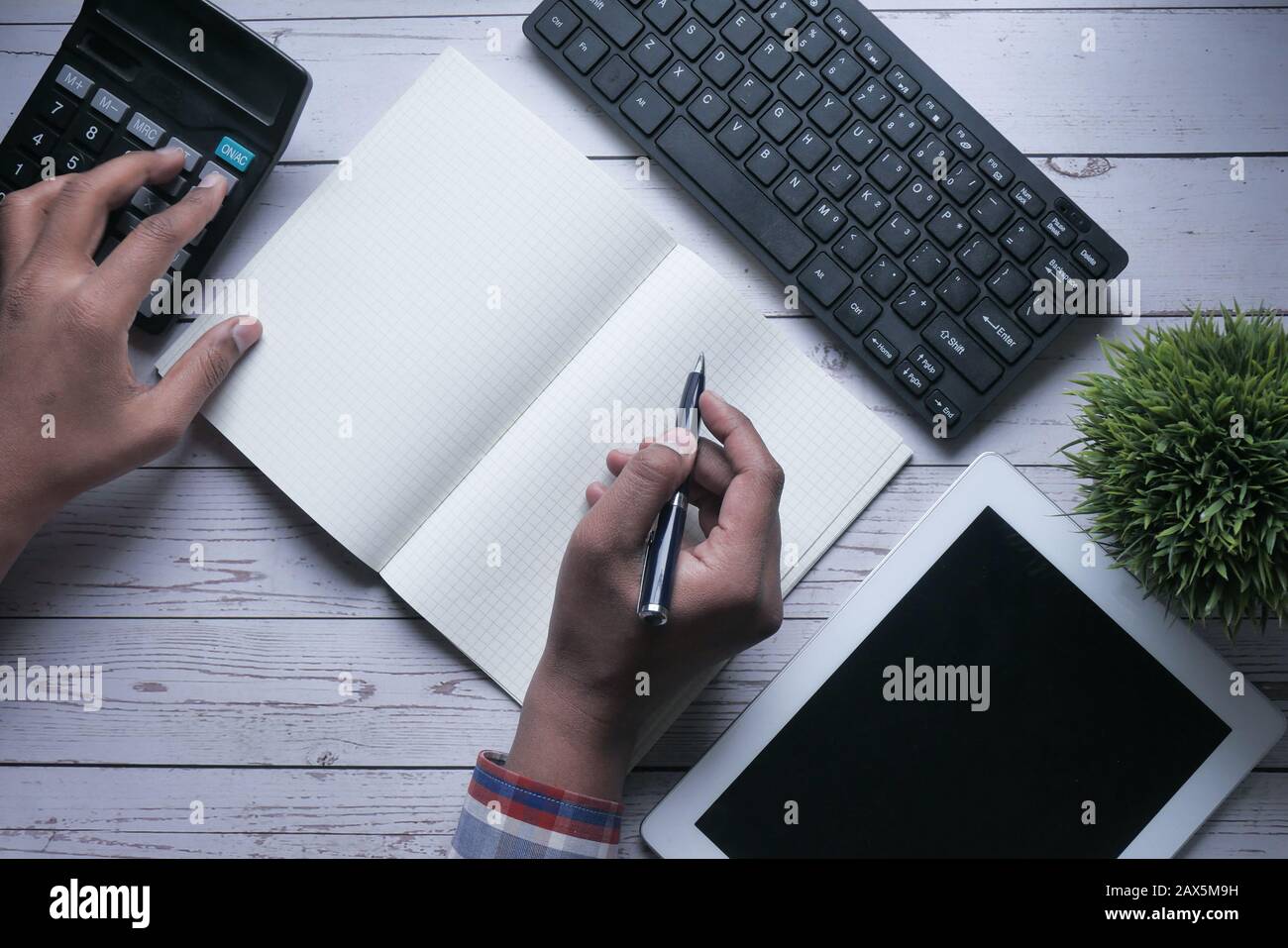 top view of man hand writing on notepad and using calculator  Stock Photo