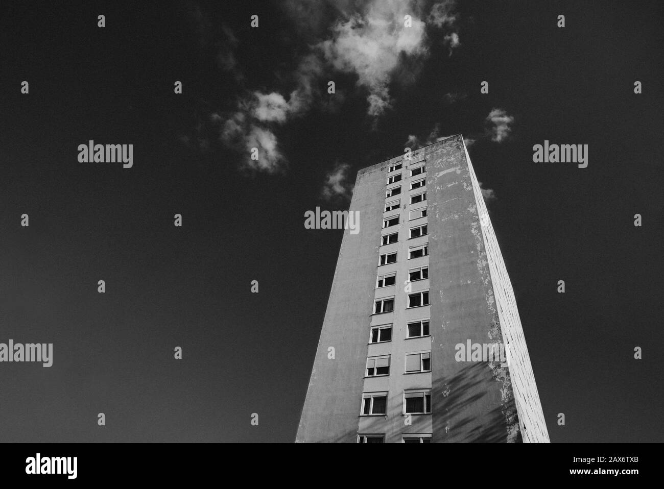 Low angle shot of a tall building against a cloudy sky in black and ...