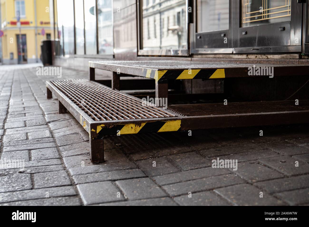 Warning tape on metal stairs outdoors by sidewalk, yellow and black stripes for attention Stock