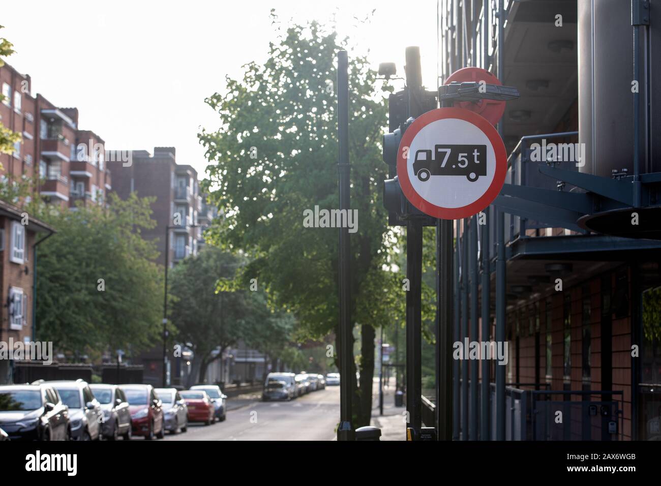 Road sign of United Kingdom for no access to trucks over 7.5 tonnes weight in street of London. Cars parked at city road Stock Photo