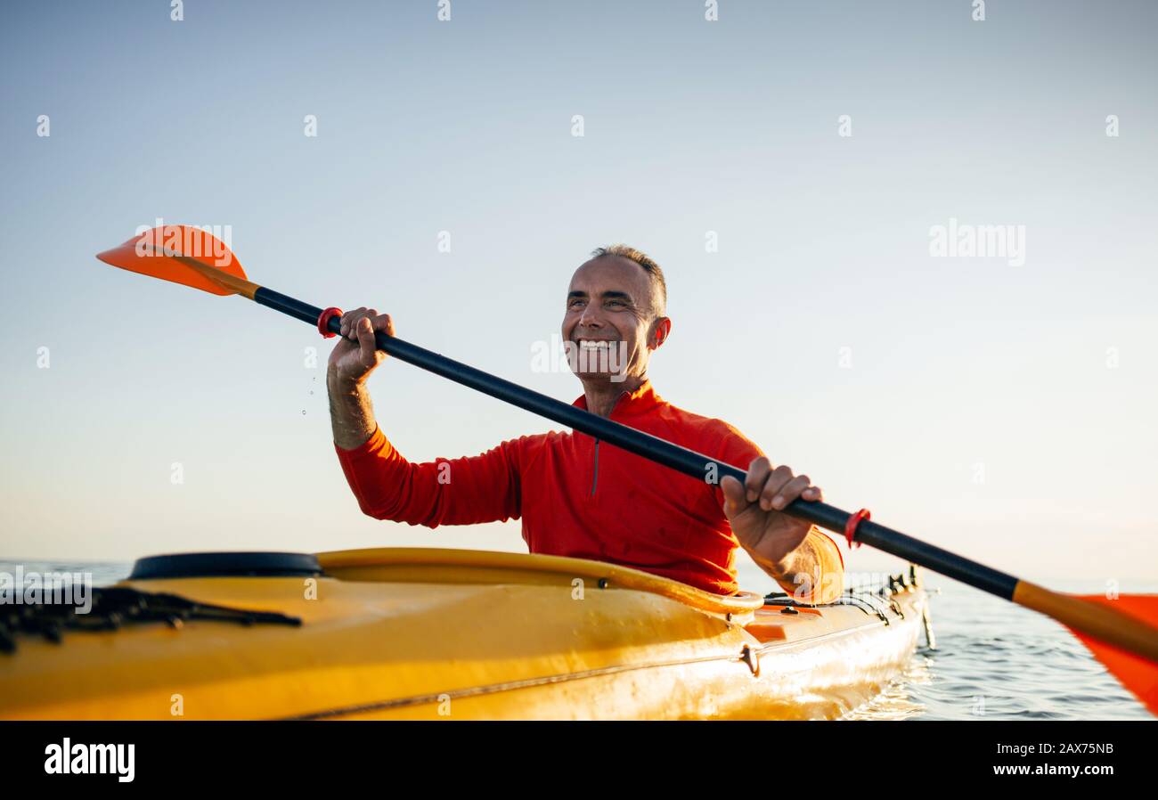Smiling senior man paddling kayak Stock Photo