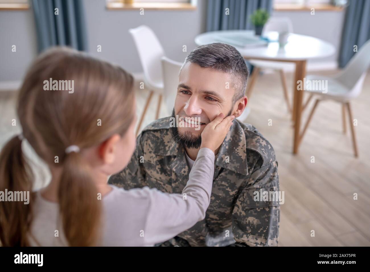 Dad in camouflage looking at little daughter. Stock Photo