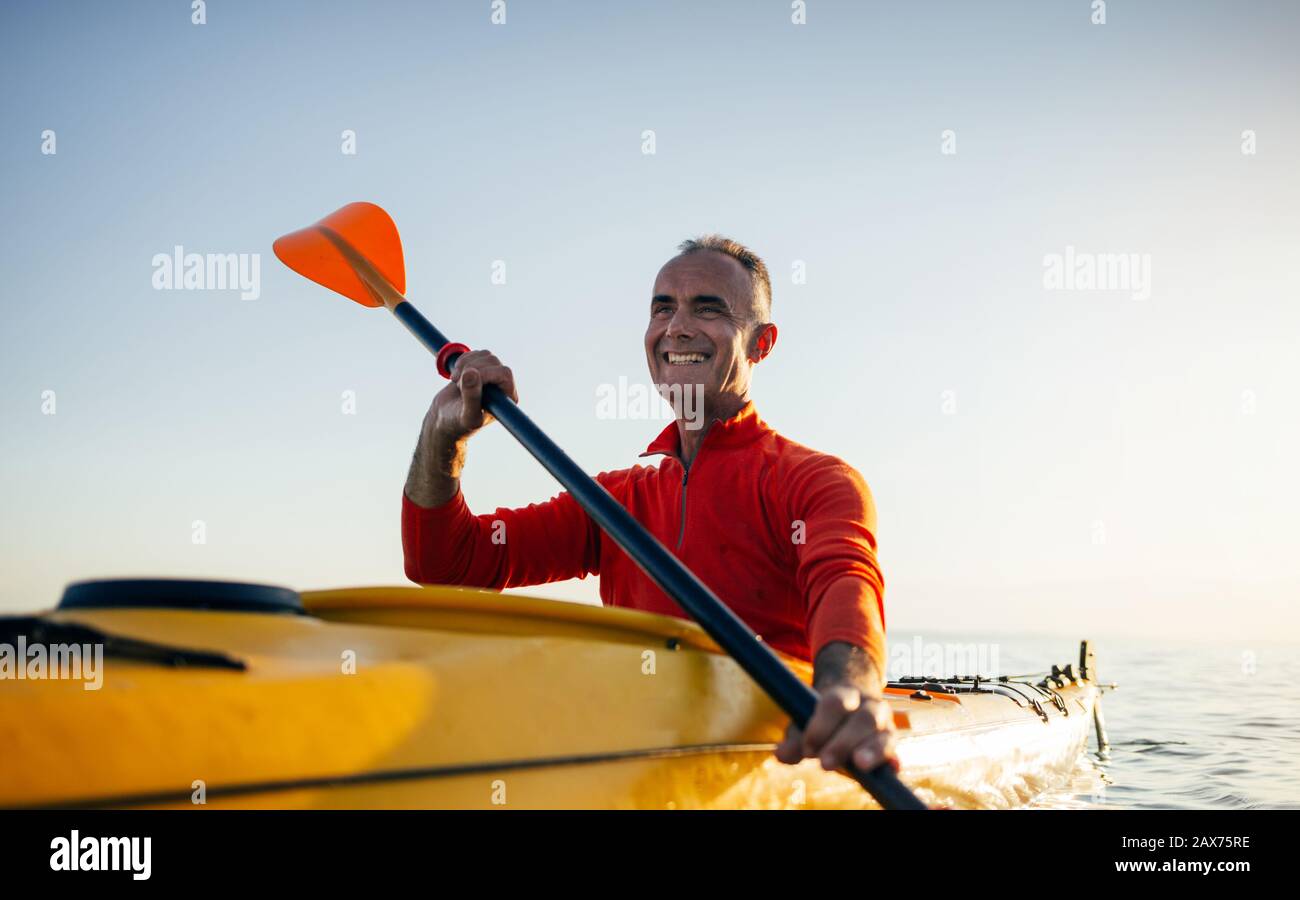 Smiling senior man paddling kayak Stock Photo