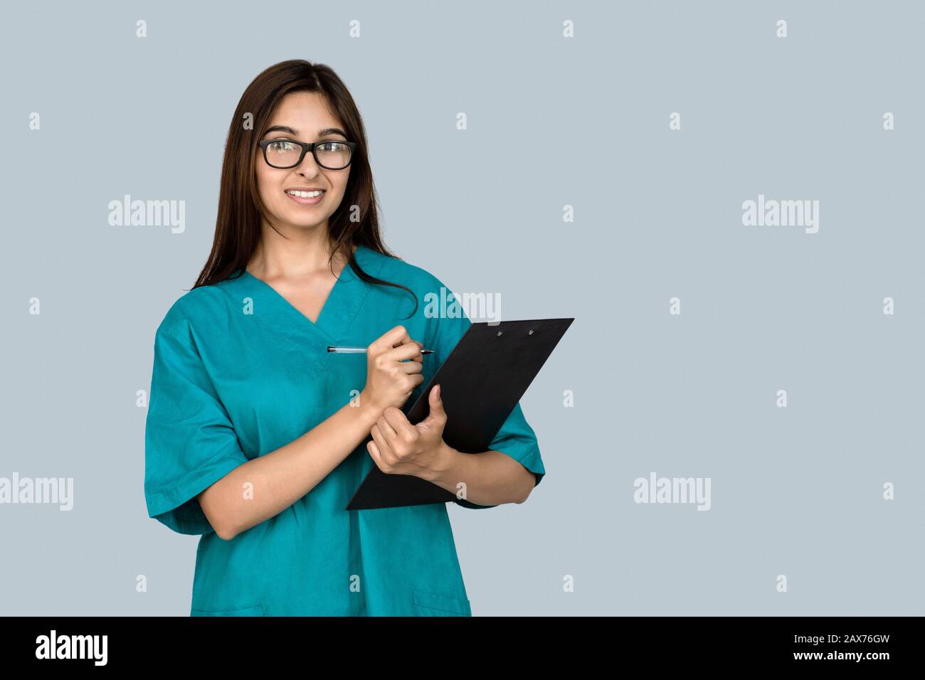 Smiling young indian woman nurse point at copy space isolate on gray background Stock Photo