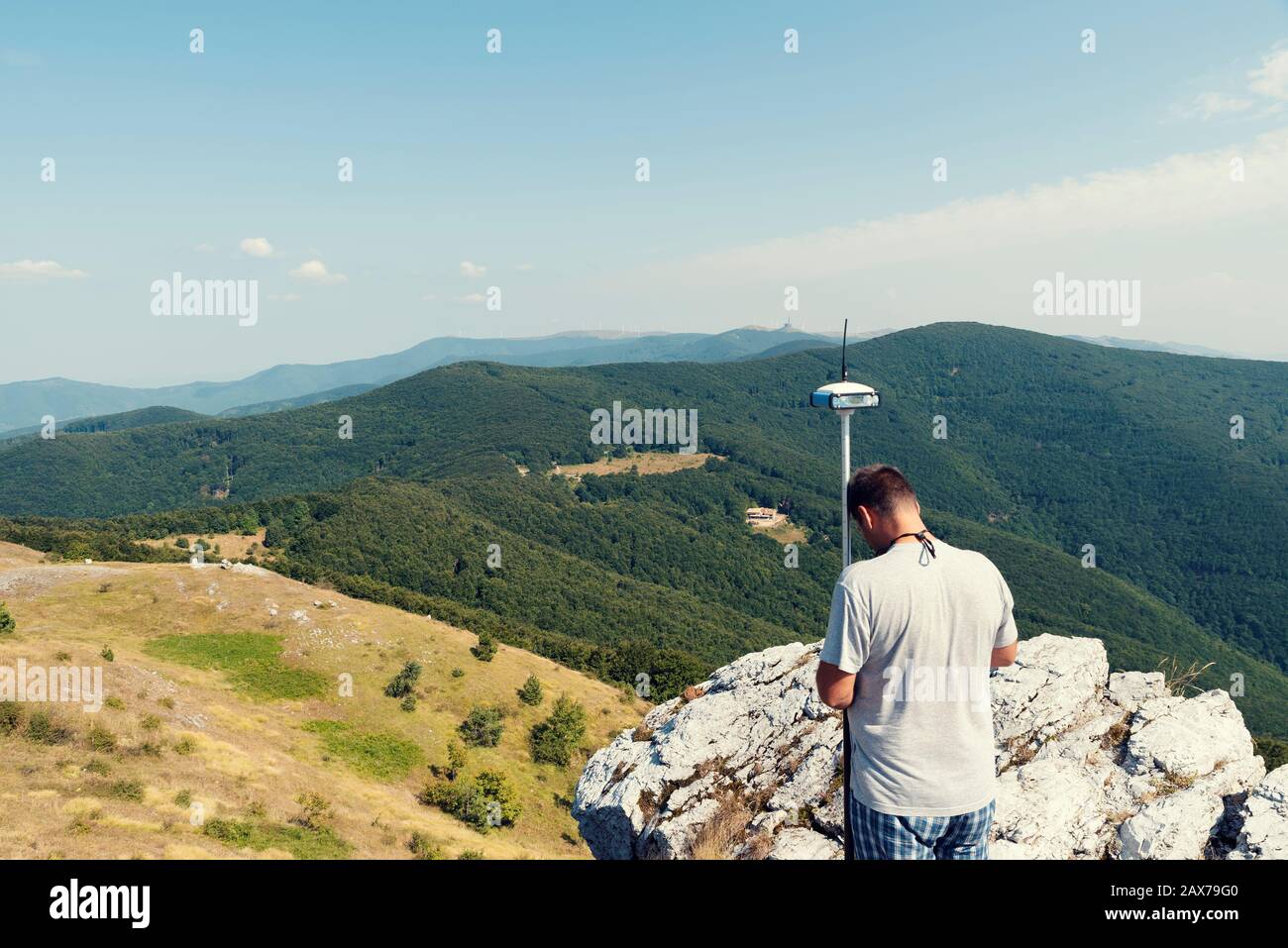 Engineer using GPS surveying equipment in mountain during the summer Selective focus Stock Photo