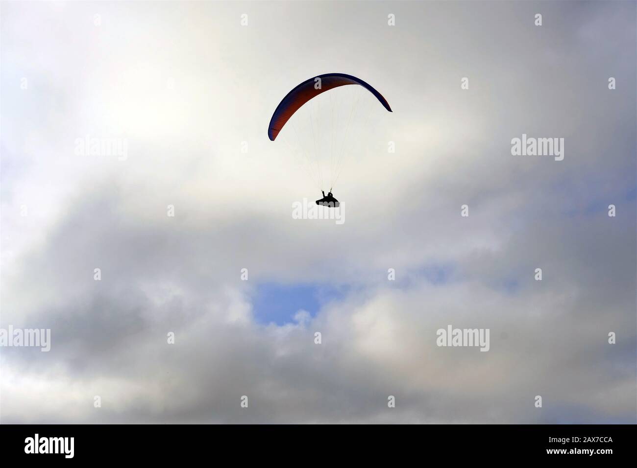 silhouette of a paraglyding man against white clouds in the sky in Malta Stock Photo