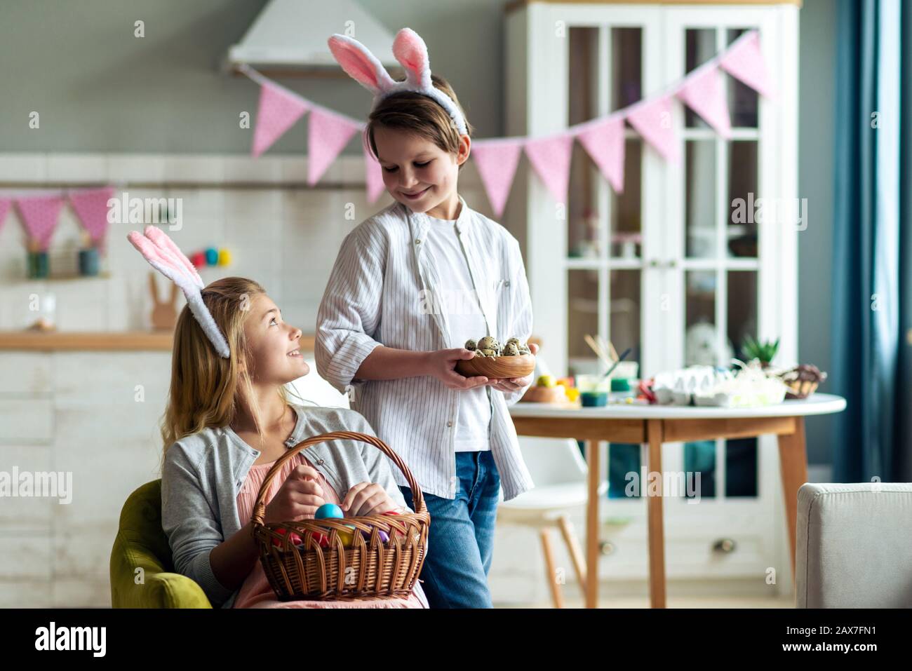 Smiling girl and boy make Easter basket at home in the kitchen Stock Photo