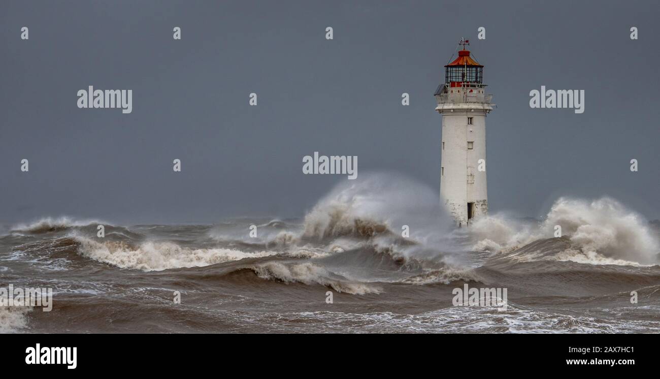 New Brighton Lighthouse at Perch Rock on the opposite side of the River Mersey to Liverpool. Taken during a storm with rough sea and high waves Stock Photo