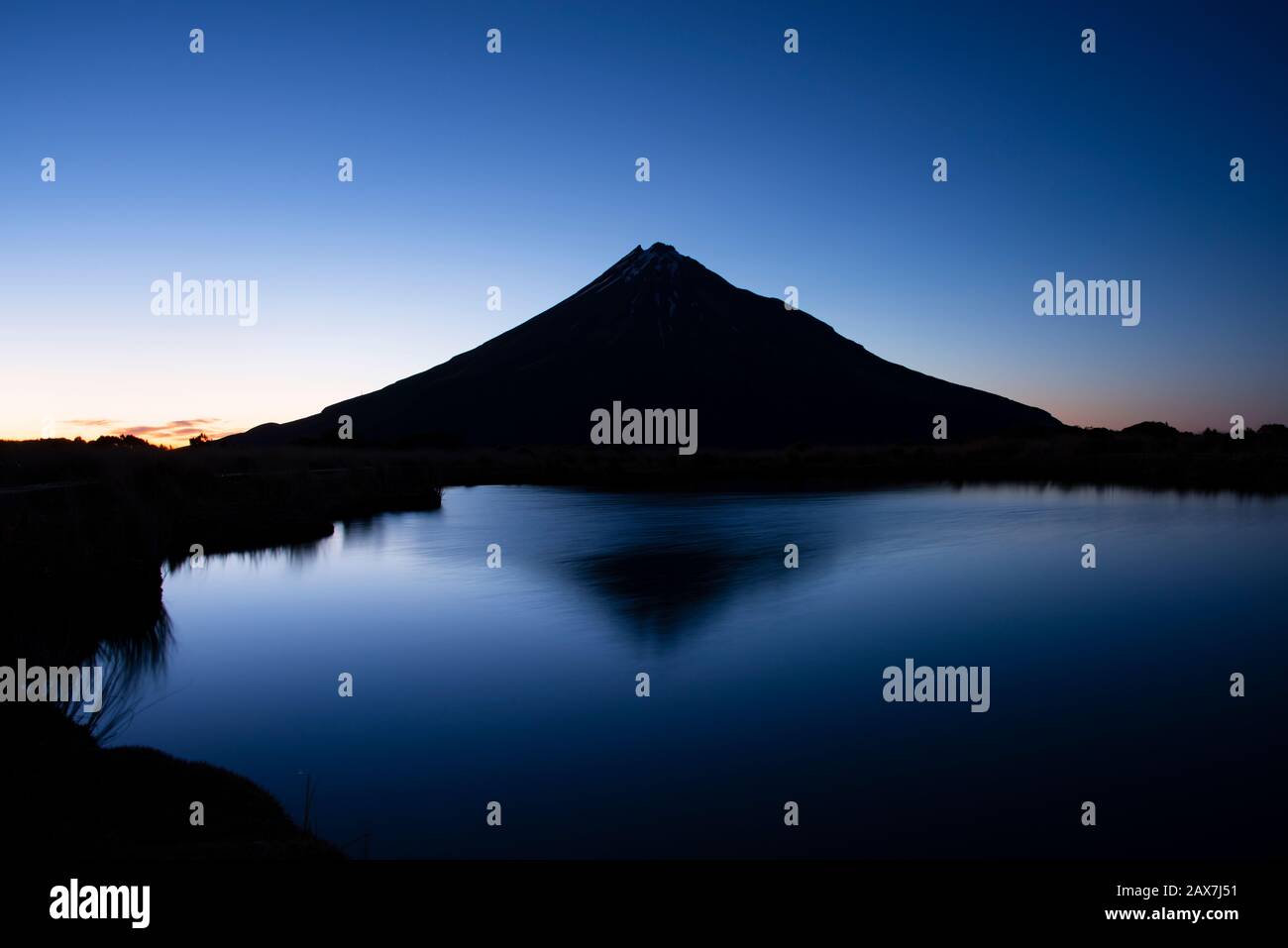 Mt Taranaki reflected in the Pouakai tarn at dawn Stock Photo