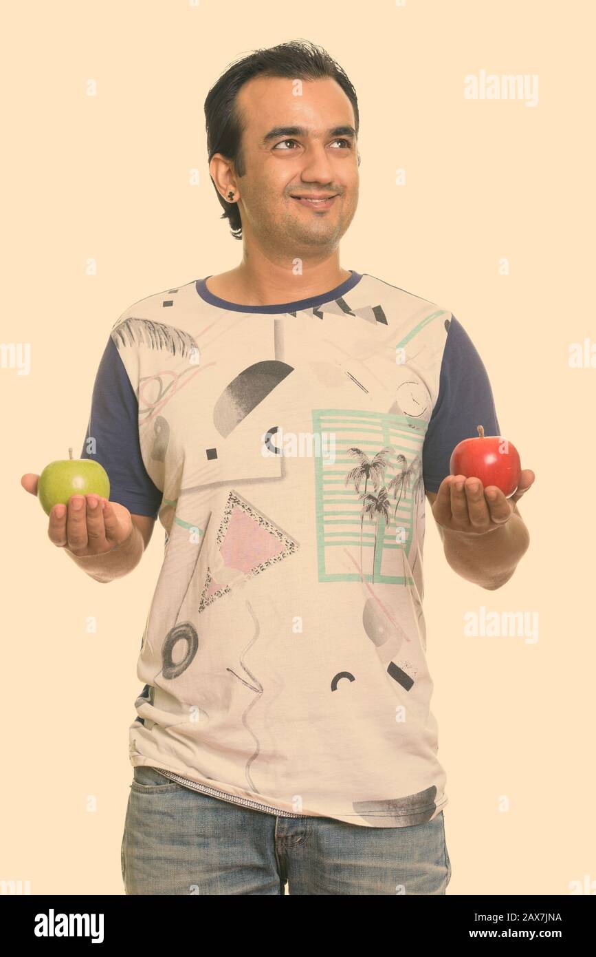 Happy Persian man smiling and holding red and green apple while ...