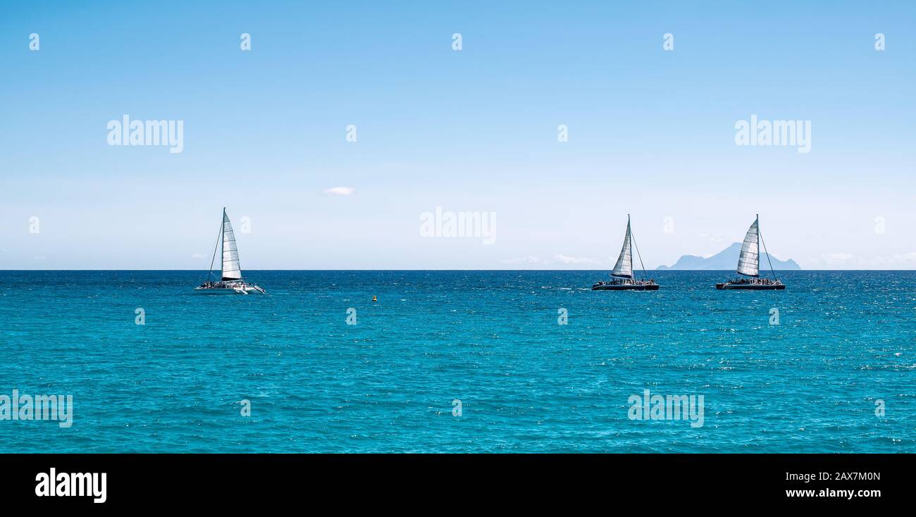 Panoramic sea view with three sailing boats cruising on the ocean. Stock Photo