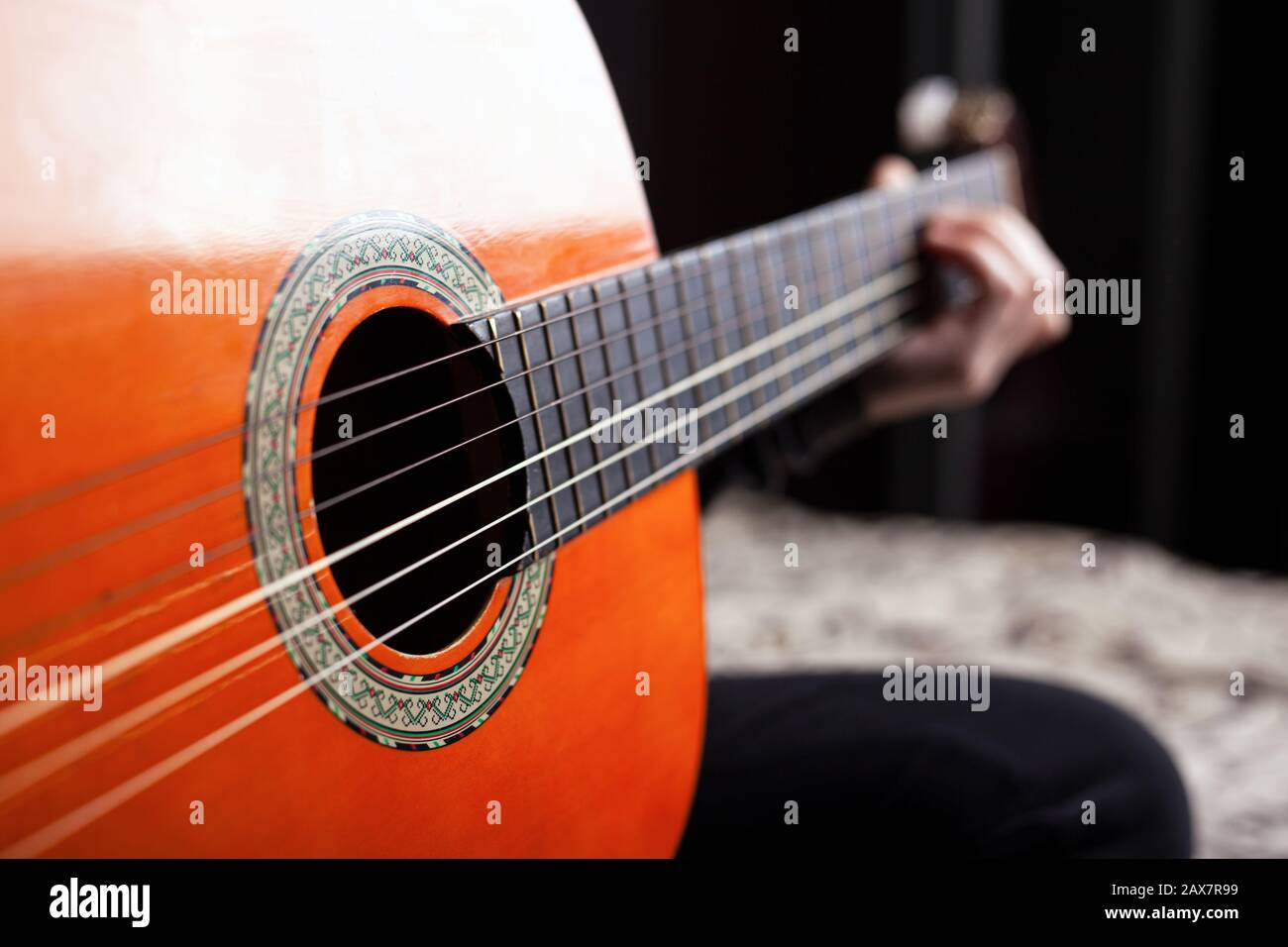 playing the classical spanish acoustic guitar orange color. Stock Photo