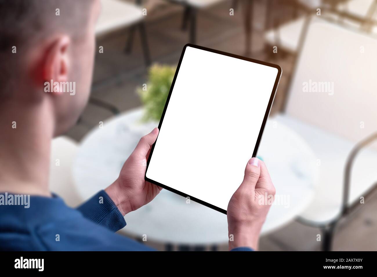 Tablet mockup in man hands in coffee shop. View over guy shoulder Stock Photo