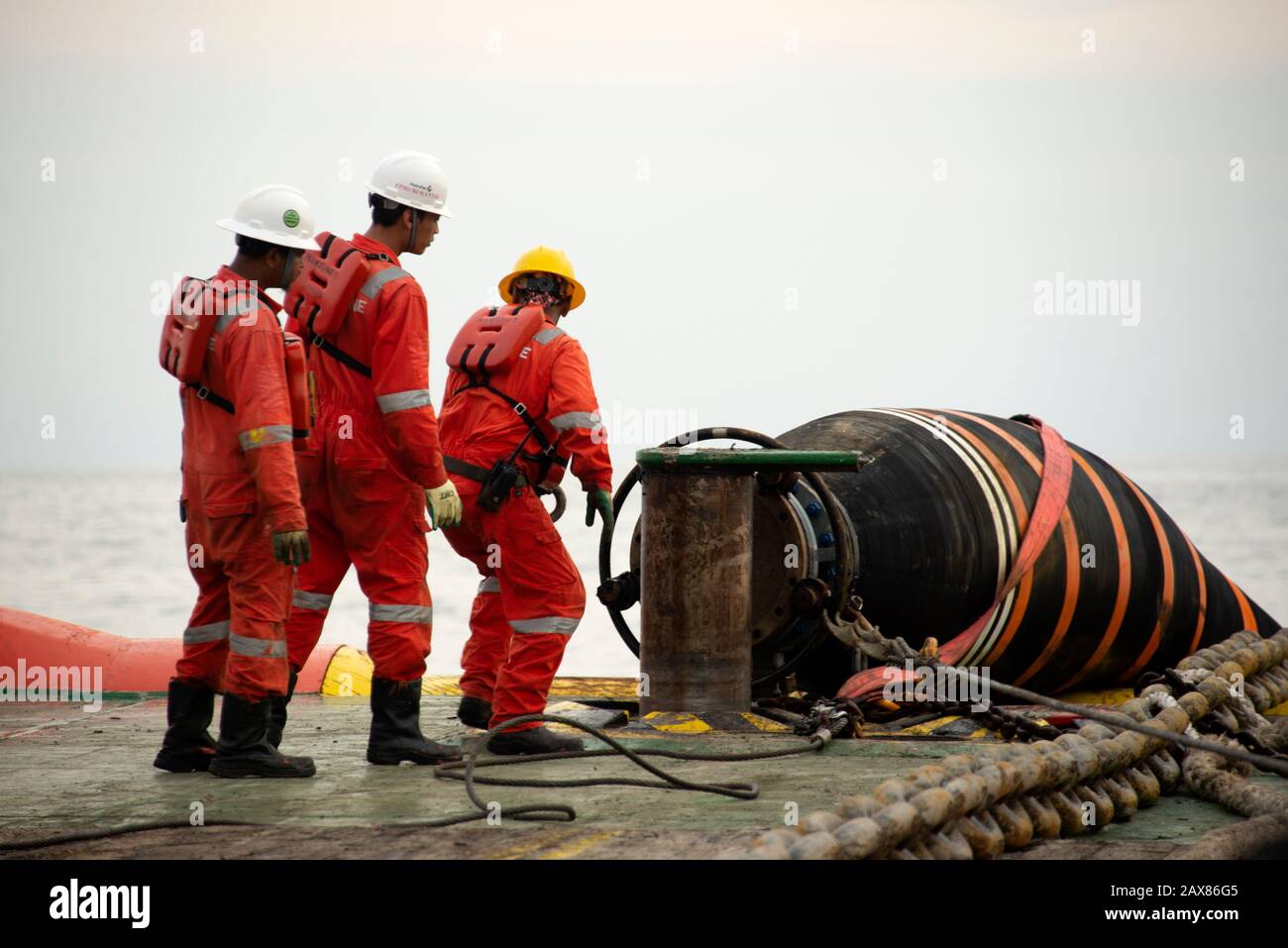 marine crew working on deck  during hose handling operation carried out at sea Stock Photo