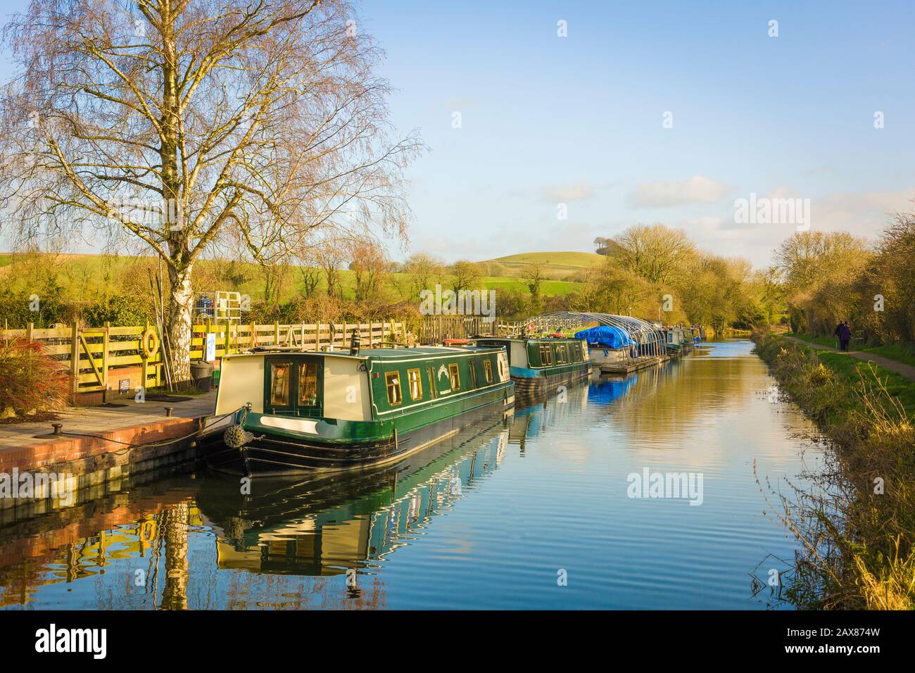 A calm sunny landscape in early January showing the Kennet and Avon canal and narrow boats moored at Honeystreet in the Vale of Pewsey in Wiltshire England UK Stock Photo