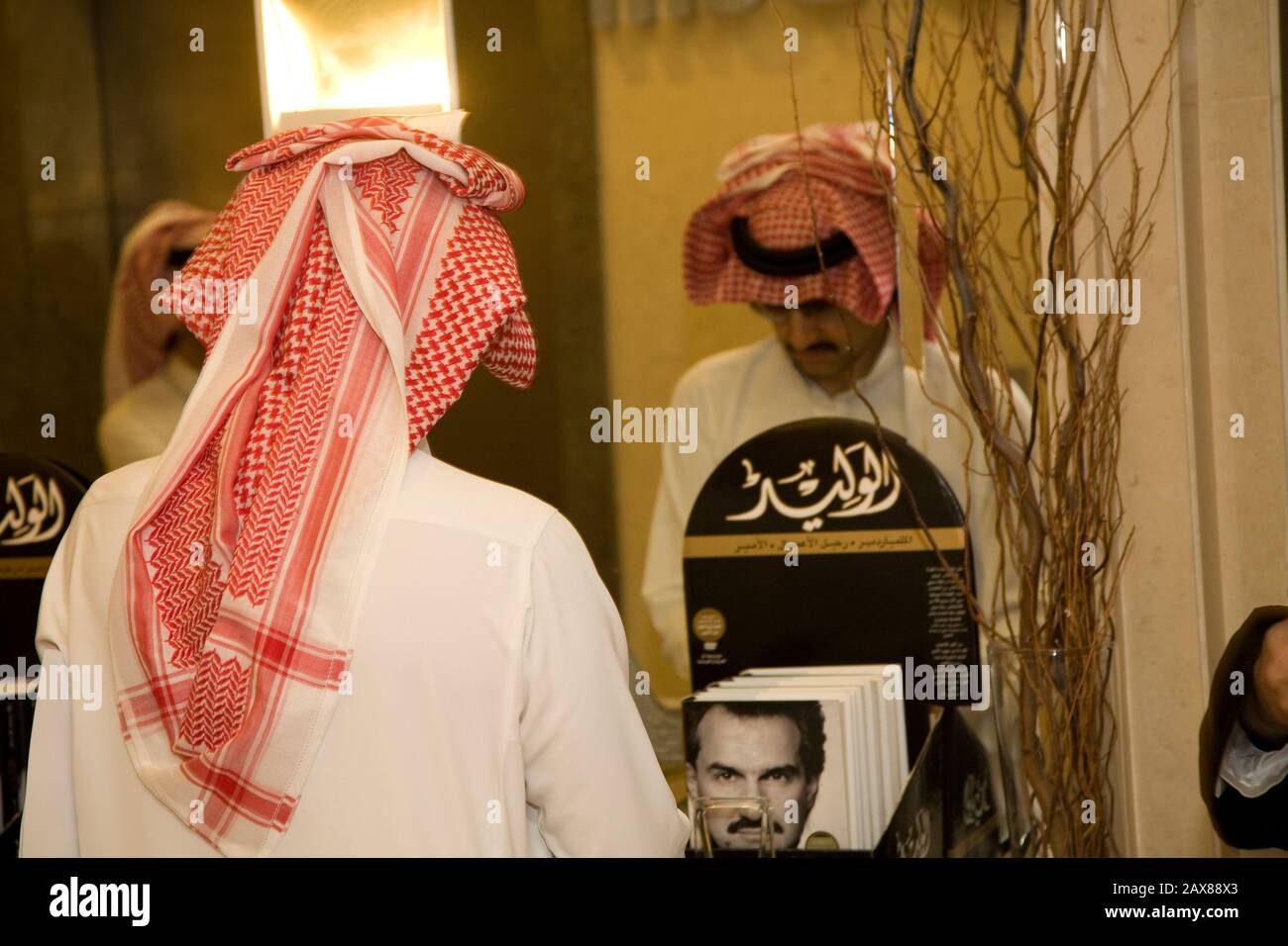 A mirror image of His Royal Highness Prince Al Waleed Bin Talal Al-Saud flipping through a stack of auto-biographies in his office at the Kingdom Holding Company, Riyadh, Saudi Arabia. Stock Photo