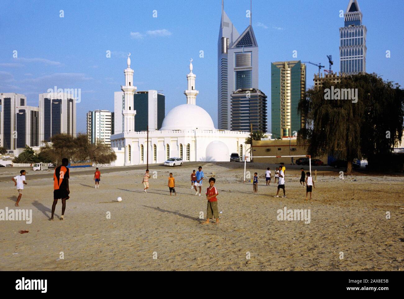 A group of boys play a game of football with the Sheikh Zayed road in the background, Dubai, UAE