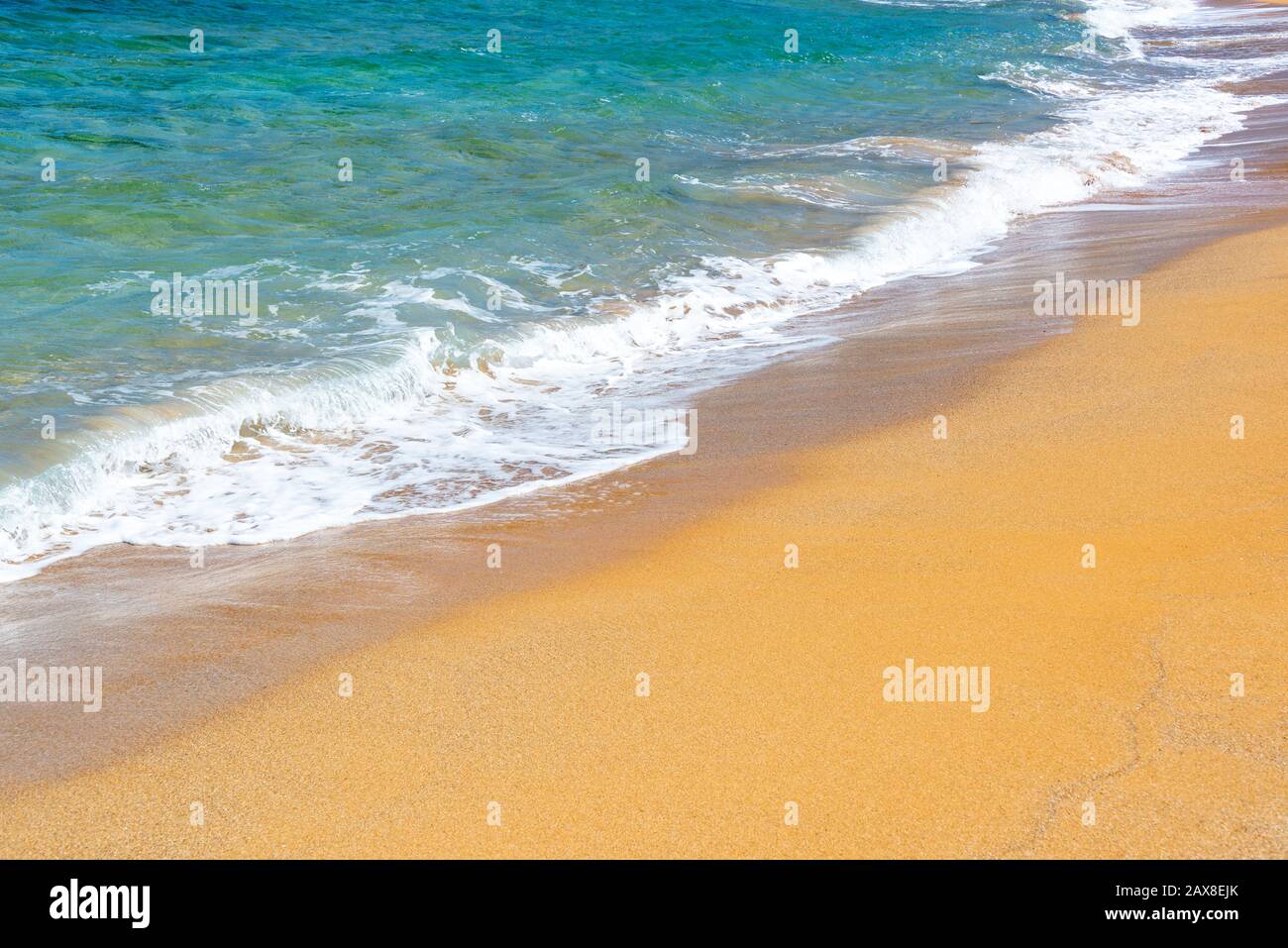 Waves on a beach with orange sand and blue water Stock Photo