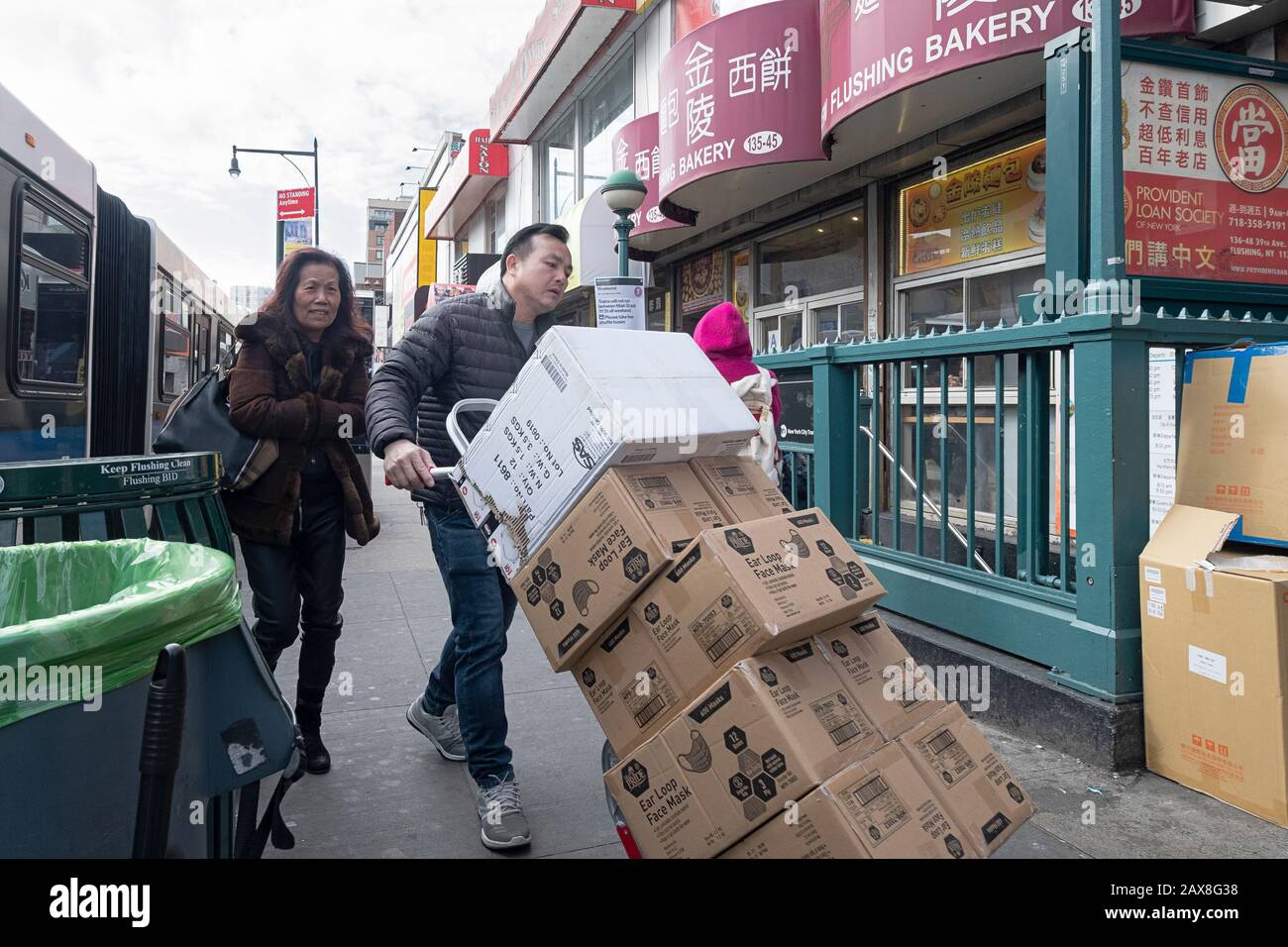 A Chinese American delivery man on Roosevelt Ave. pushing cartons of SURGICAL MASKS during the time of the coronavirus scare. In Flushing, Queens, NYC Stock Photo