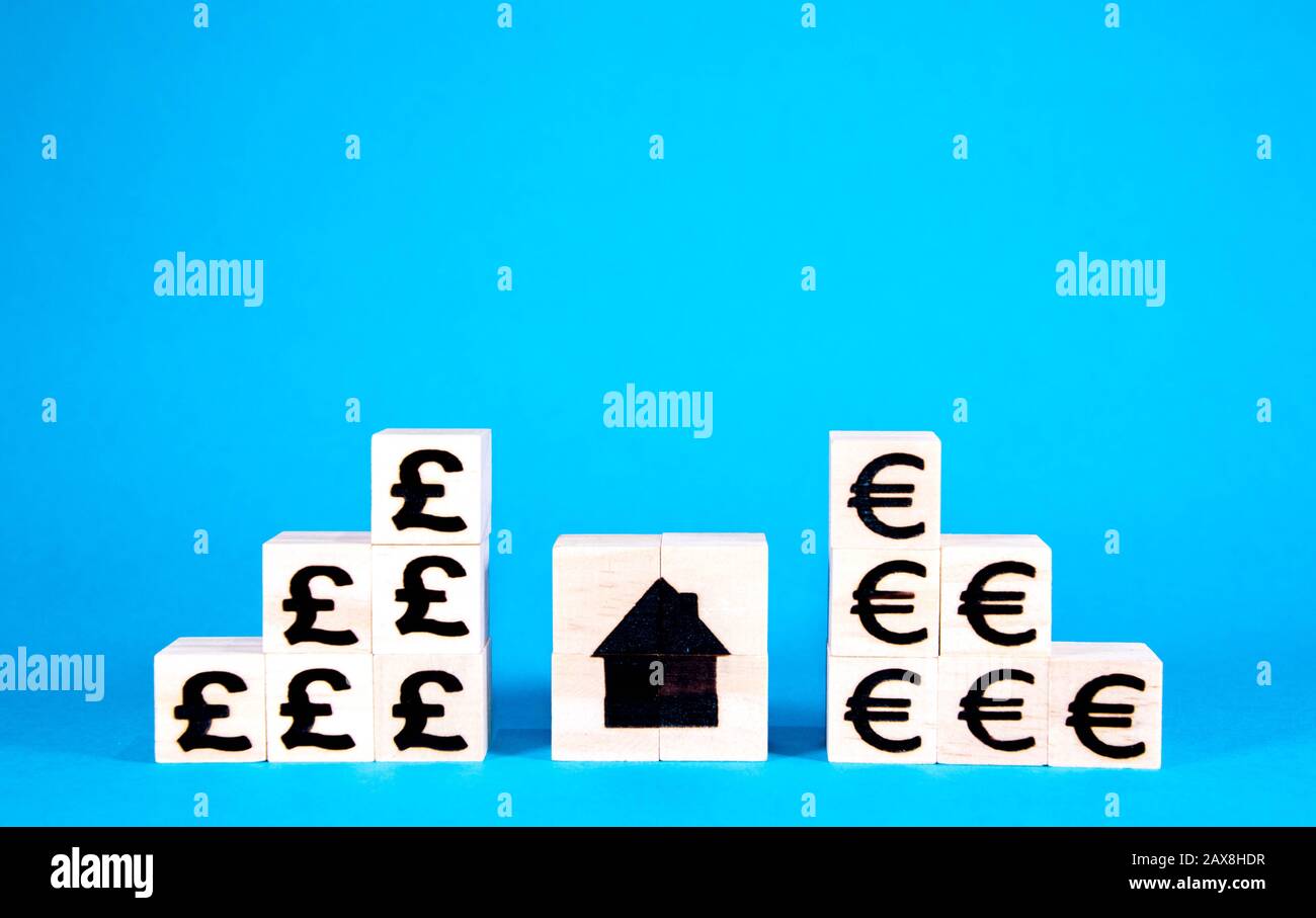 The cost of housing is a huge issue nationally and internationally. Here wooden blocks with symbols of currency show the rising costs of property inve Stock Photo