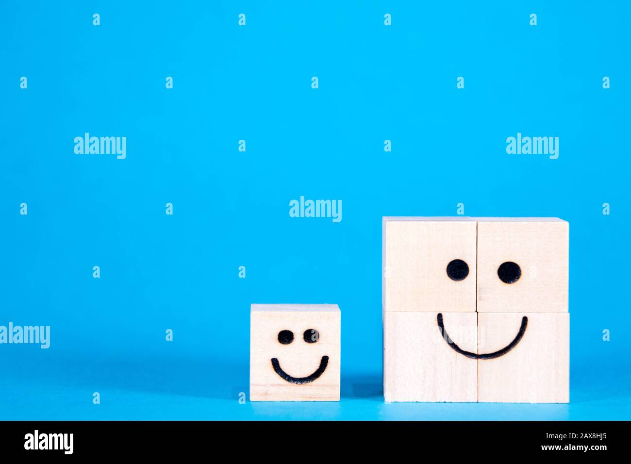 Two wooden blocks with happy faces, smile as they stand side by side. Stock Photo