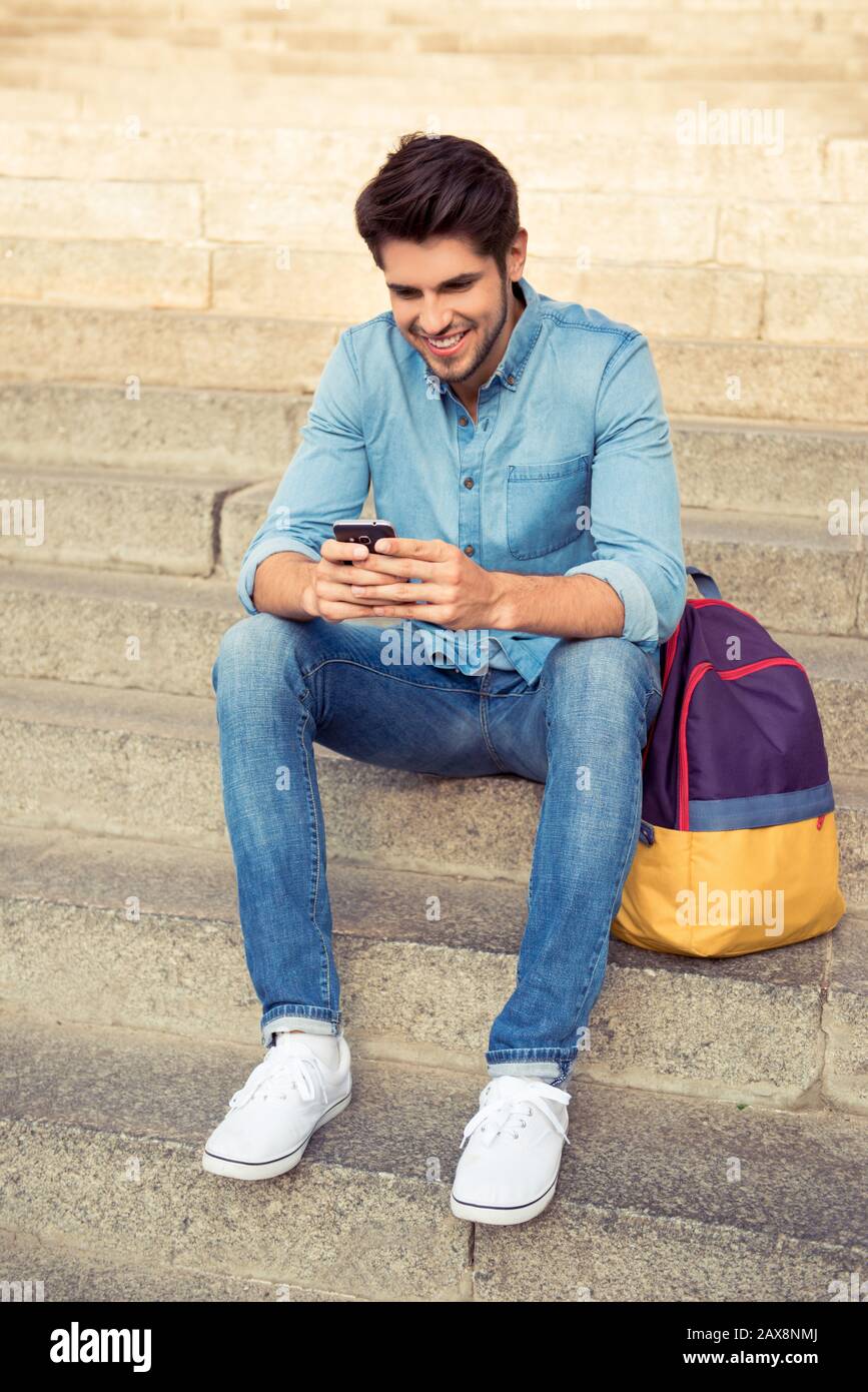 happy smiling young man sitting on the stairs with phone Stock Photo ...
