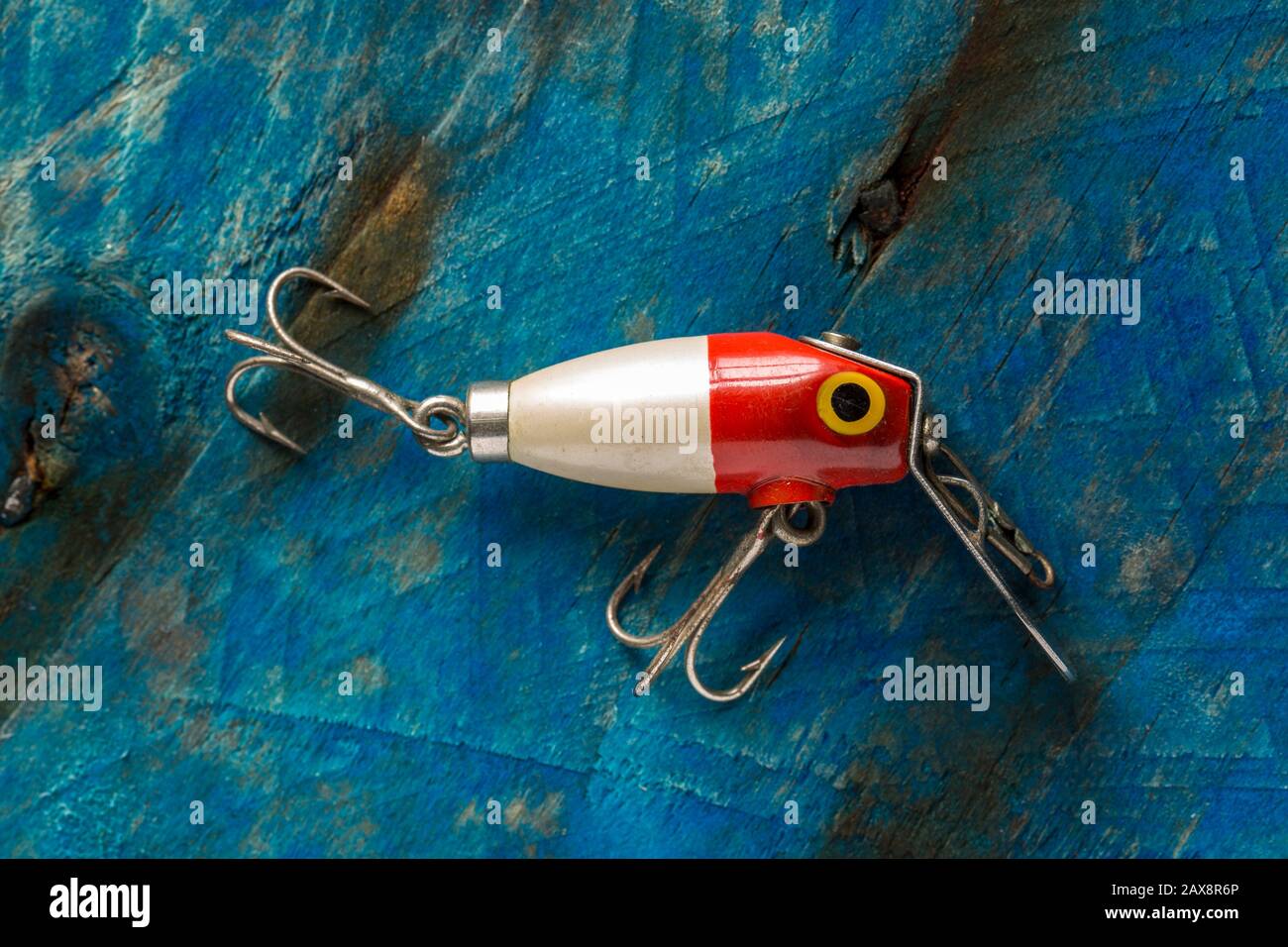 An old fishing lure, or plug, equipped with treble hooks designed to catch predatory fish. The lure has possibly been made by Woods Mfg, but this cann Stock Photo