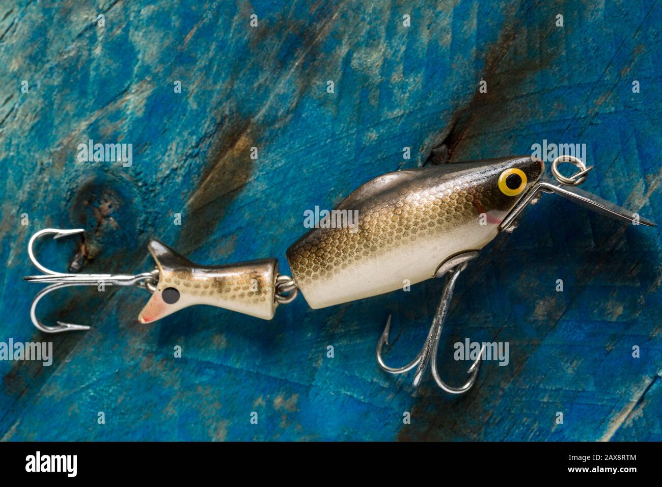 An old fishing lure, or plug, equipped with treble hooks designed to catch predatory fish. The lure has possibly been made by Woods Mfg, but this cann Stock Photo