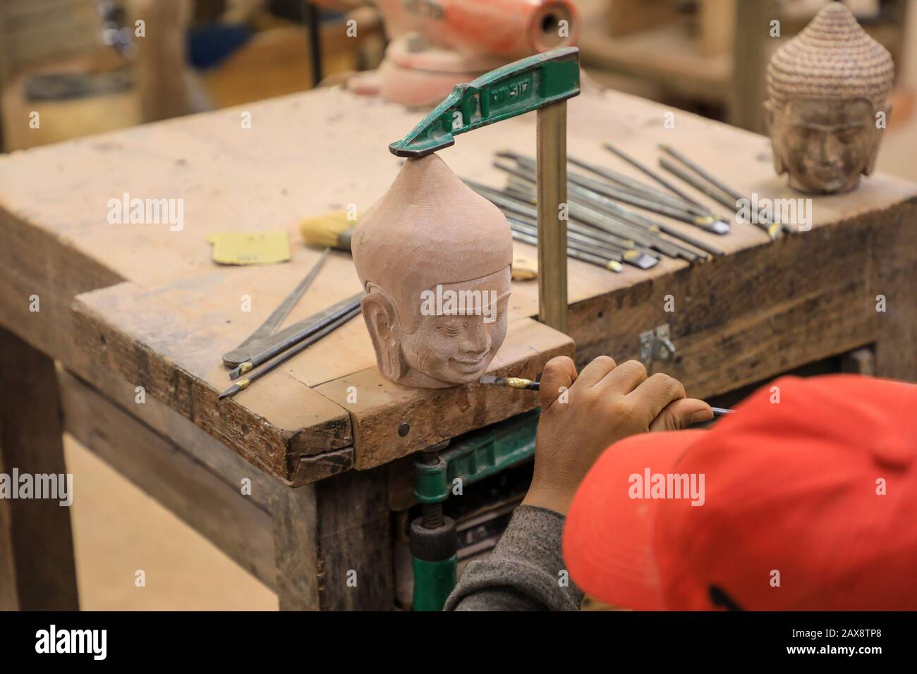 A man using a chisel to carve stone heads at Artisans d'Angkor, a worker co-operative workshop, Siem Reap, Cambodia Stock Photo