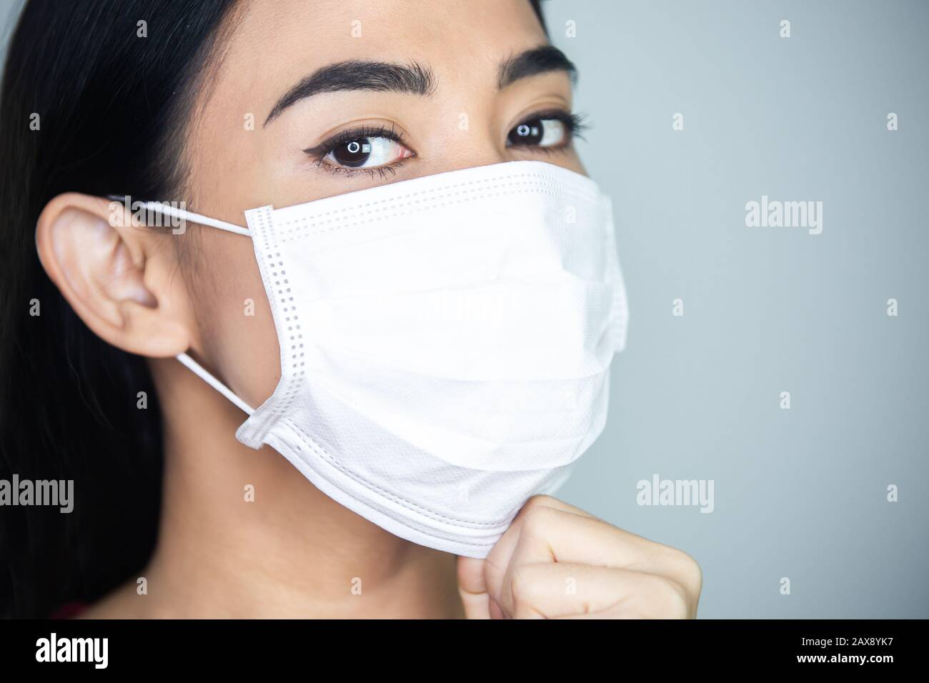 A woman wearing medical disposable mask to avoid contagious viruses. Stock Photo