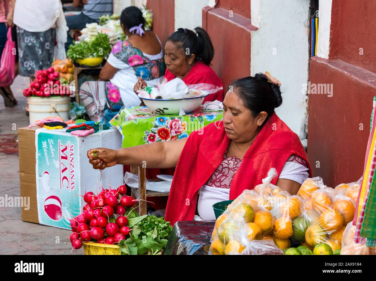 Woman selling vegetables and fruits, wearing huipil, traditional hand