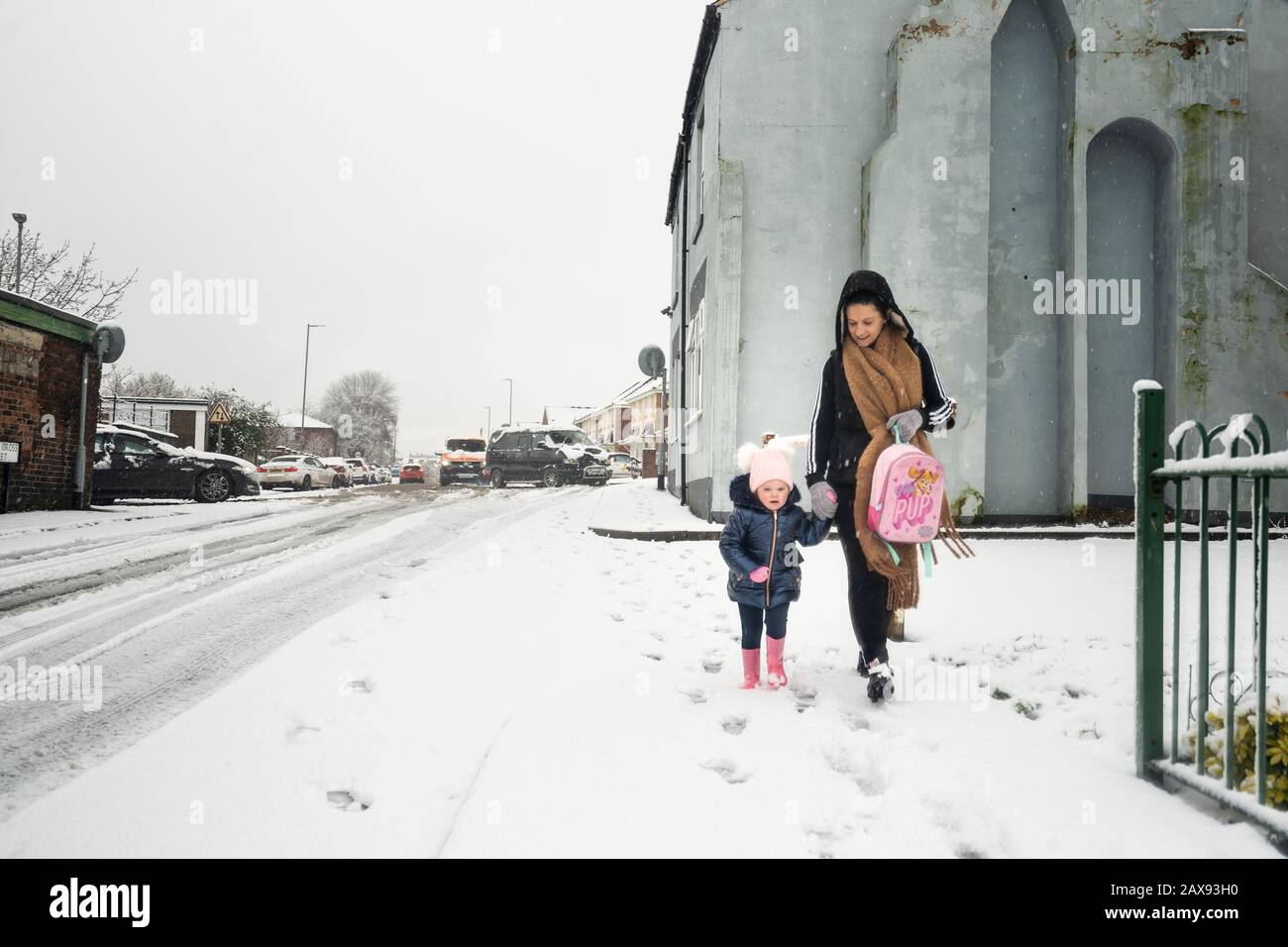 Pretty little girl walking with her mother, toddler experiencing her first time in the snow, after heavy snowfall, Nursery closure due to snow Stock Photo
