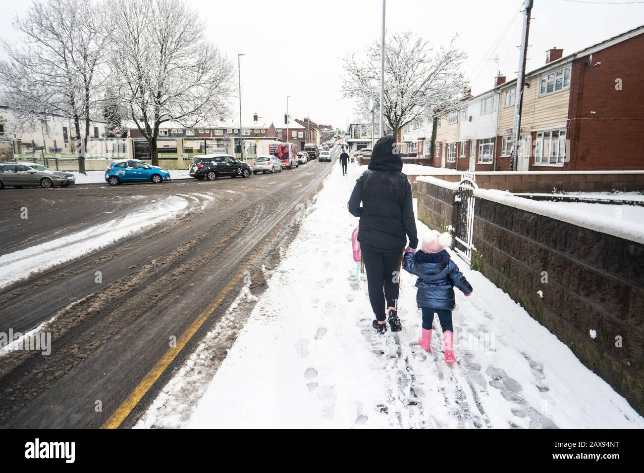 Pretty little girl walking with her mother, toddler experiencing her first time in the snow, after heavy snowfall, Nursery closure due to snow Stock Photo