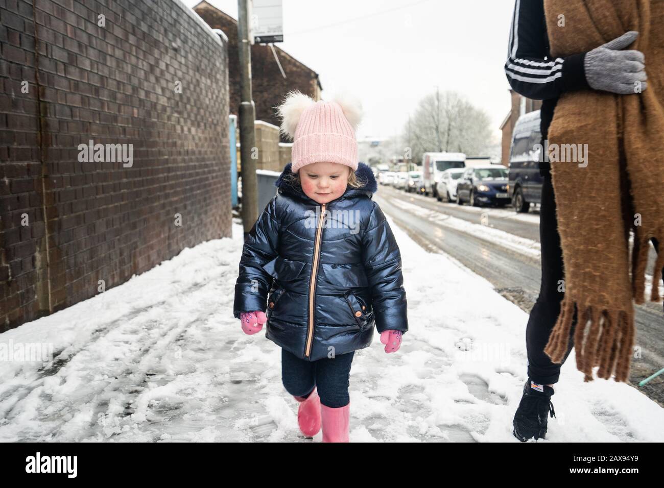 A pretty little girl, toddler walking and experiencing her first time in the snow, after heavy snowfall in Stoke on Trent, Longton, Nursery closure Stock Photo