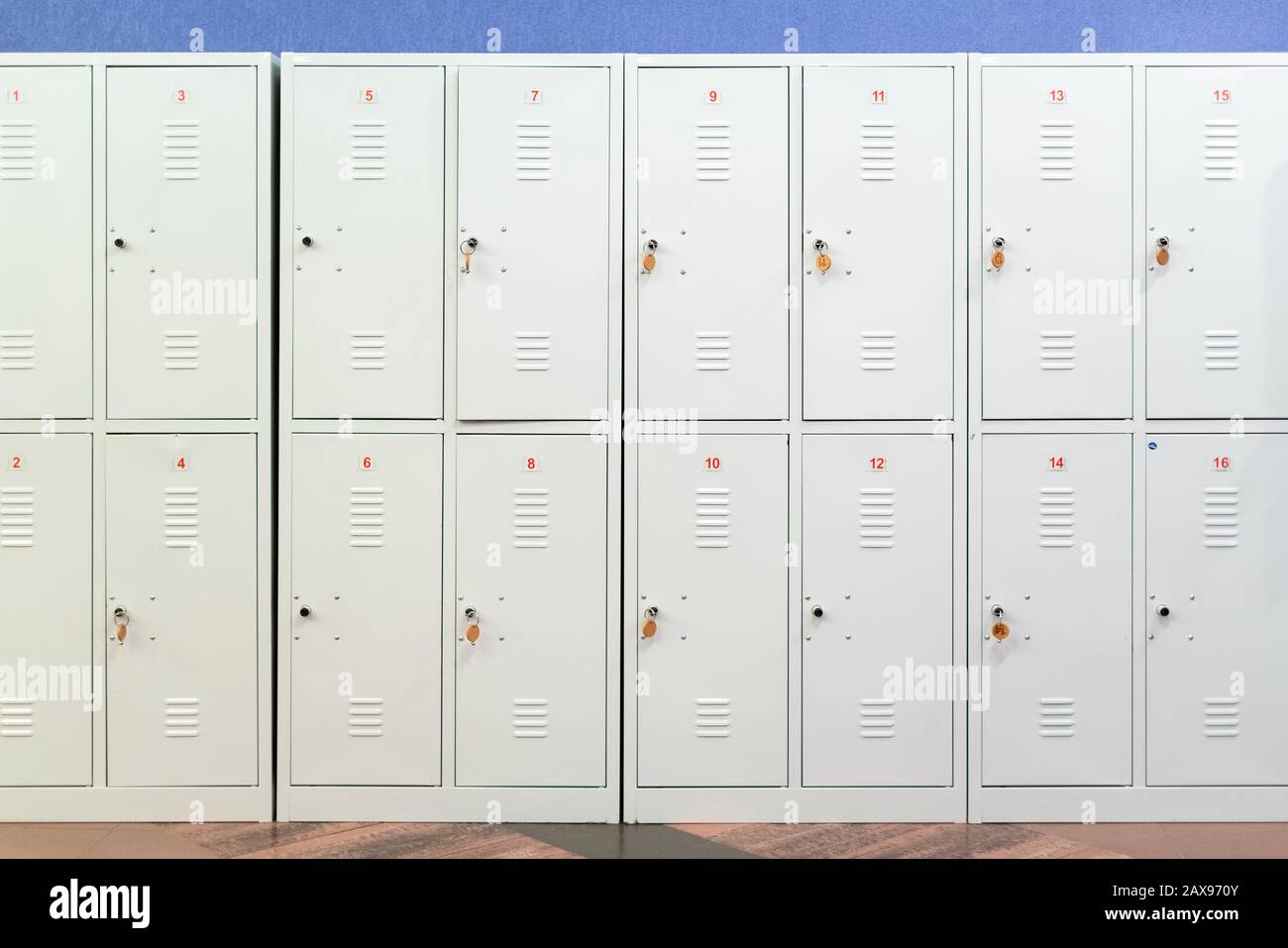 A row of grey metal school lockers with keys in the doors. Storage
