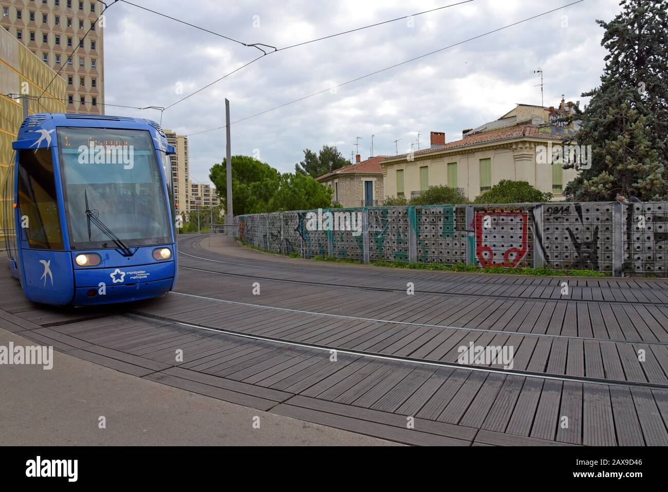 A Montpellier tram on the elevated section of the network alongside traditional housing near the city centre, Montpellier, France Stock Photo