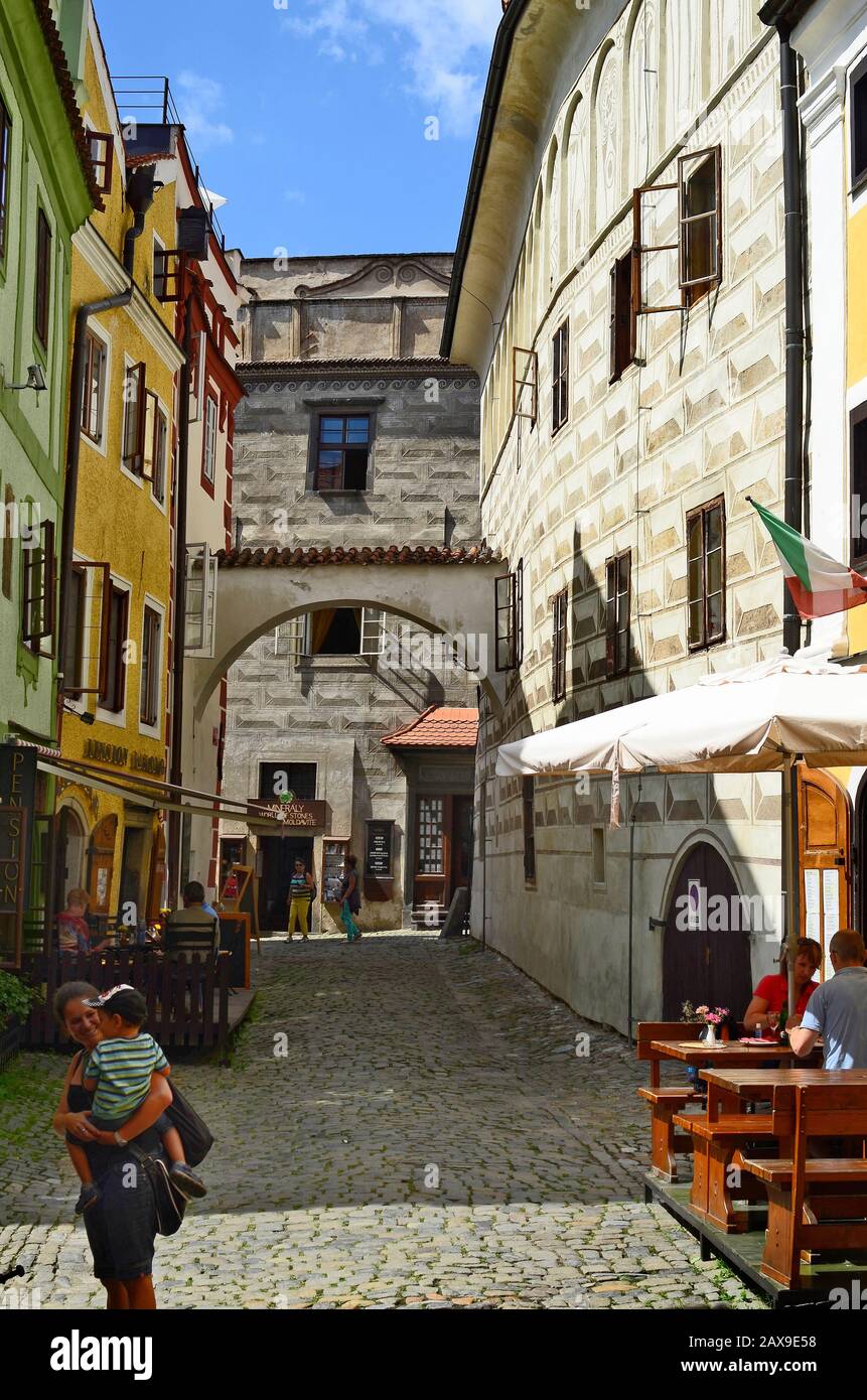Cesky Krumlov, Czech Republic - August 11th 2013: Unidentified tourists, arch, street cafe and coloured houses with sgraffito decorated facade in the Stock Photo