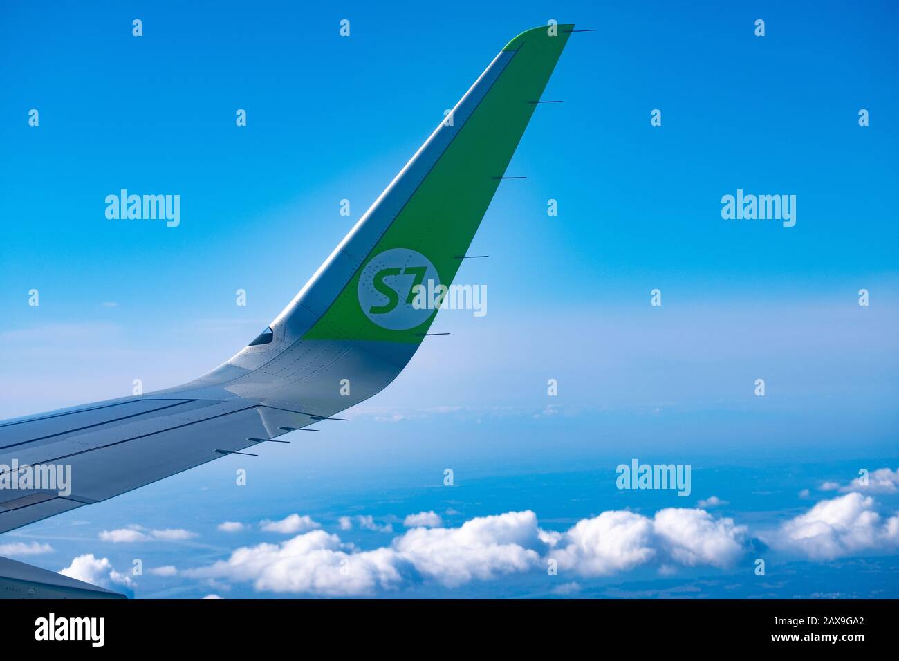 The wing of the S7 airline plane from the window over Tokyo. View of the clouds in the daytime. Stock Photo